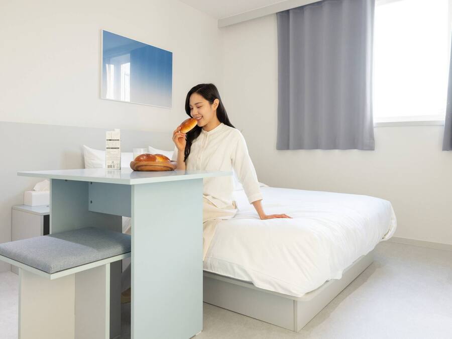 Um quarto moderno com cama, mesa de cabeceira e janela com cortinas.