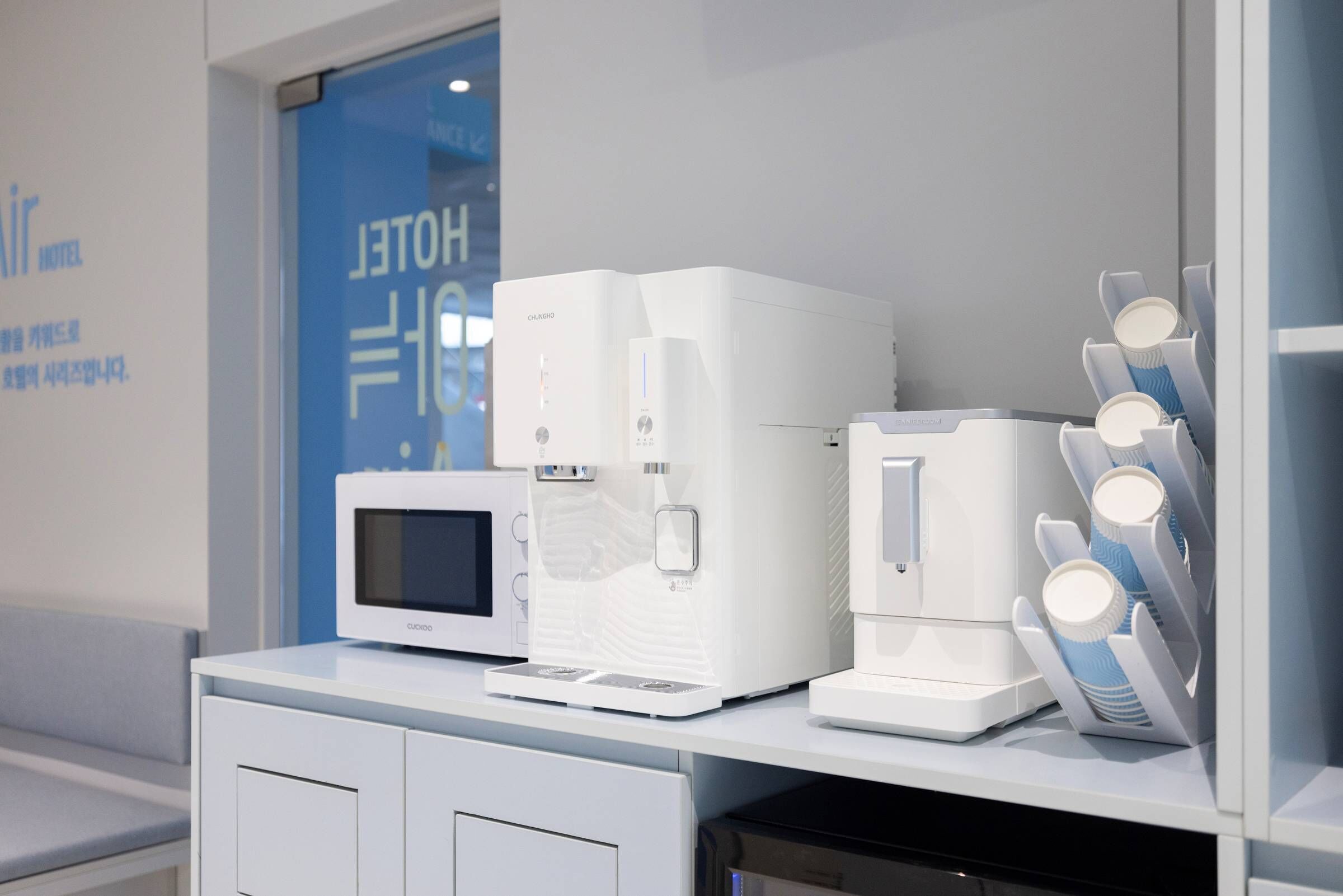 Un área de kitchenette con microondas, cafetera y dispensador de toallas de papel.