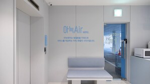 Un hall d’hôtel moderne, doté d’un banc, d’un écran numérique et d’une porte vitrée donnant sur l’extérieur.