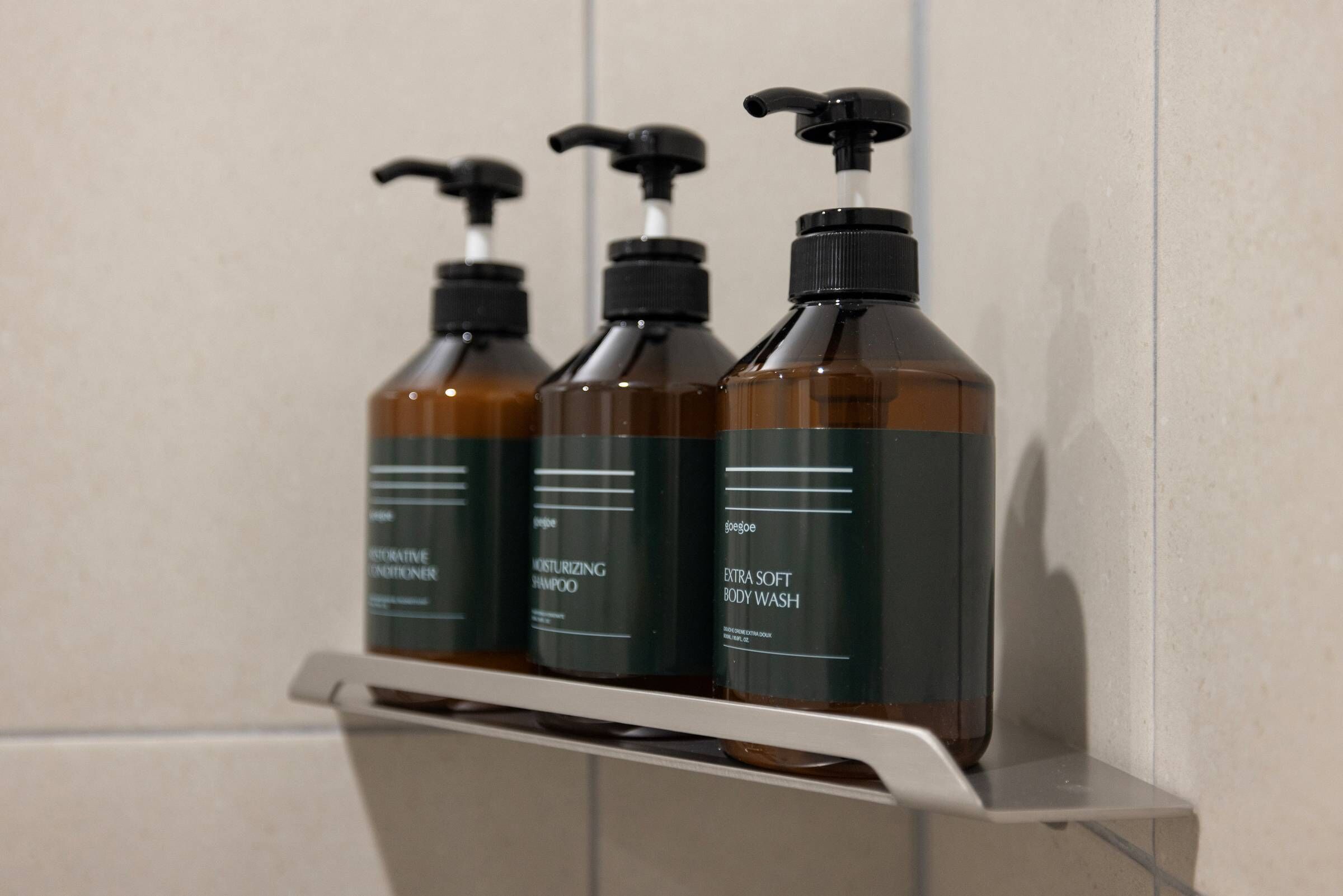 Three bottles of body wash on a white shelf.