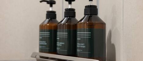 Three bottles of body wash on a white shelf.