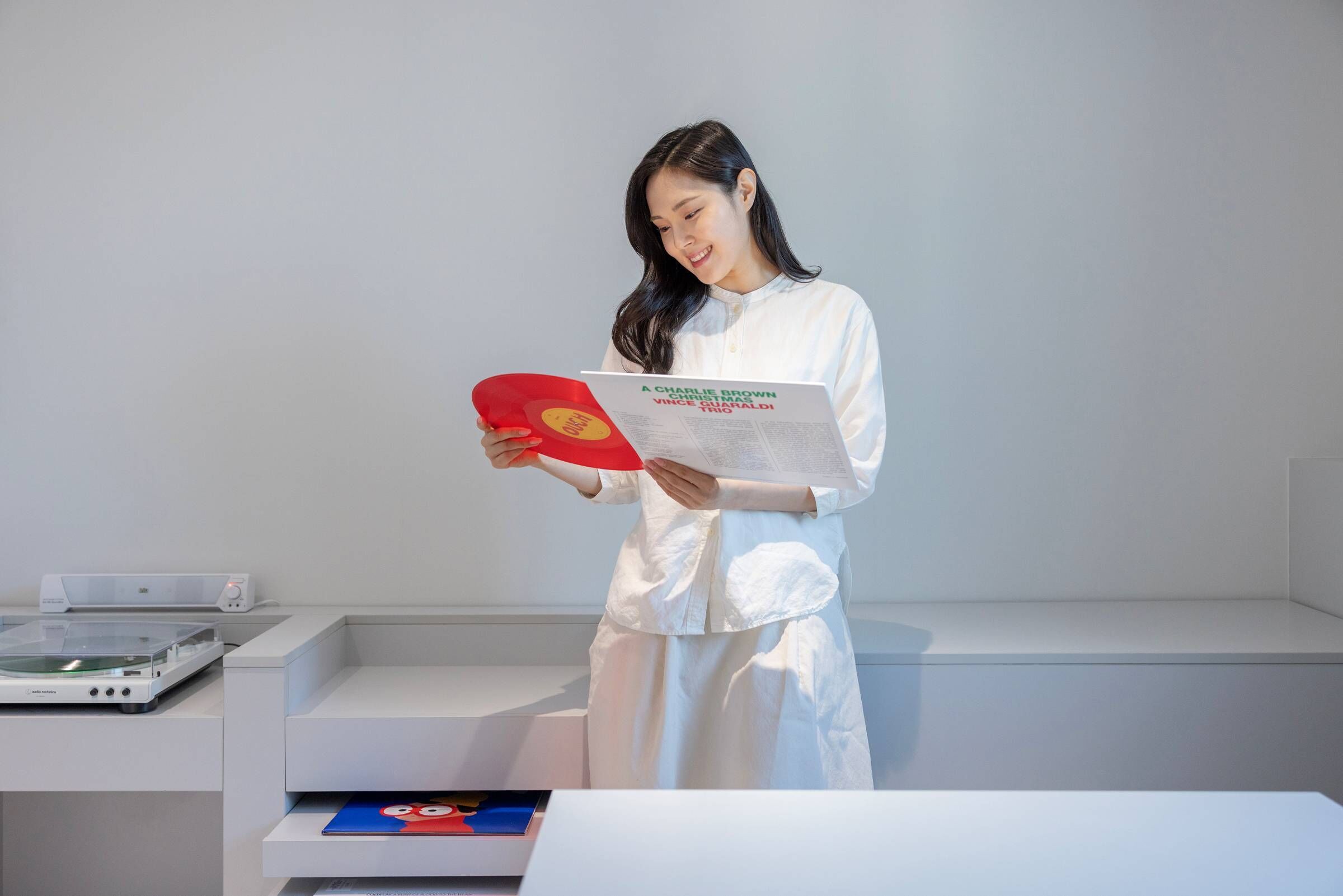 A person in a white robe holding a book titled "A CHARLIE BROWN VINCENT MAULDIN THO CALDI" and a red object.