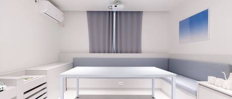 Una habitación moderna y minimalista con un escritorio blanco, una banca y un ventanal con cortinas grises.