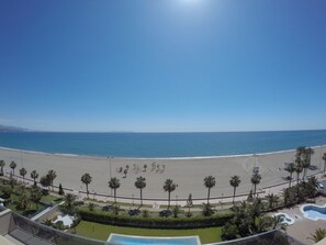 Blick auf einen Strand mit Pool und Palmen.