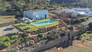A modern villa with a swimming pool, stone walls, and a view of the surrounding hills. - Can Verdal by Interhome (Sant Miquel de Balasant)