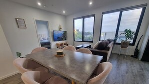 Uma sala de estar moderna com área de jantar, janelas amplas e vista para o exterior.
