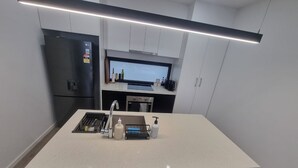 Uma cozinha moderna com ilha central, eletrodomésticos embutidos e bancada elegante.