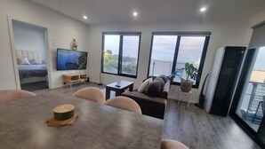 Uma sala moderna com área de jantar, janelas amplas, TV de tela plana e varanda.