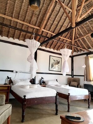 A room with two beds, a chair, a table, and a ceiling with wooden beams. - Baraka Camp (Isiolo)