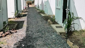 A pathway lined with white buildings, a gravel path, and a green canopy overhead. - Baraka Camp (Isiolo)