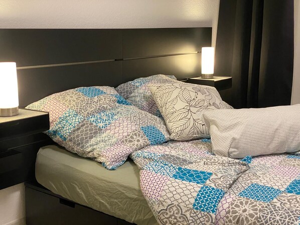 A neatly made bed with patterned bedding and two bedside lamps.