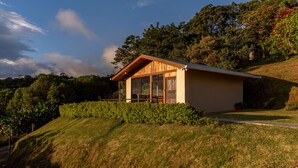 A modern house with a sloped roof, large windows, and a wooden deck. - Cabina Mandarina  (Provincia de Puntarenas)