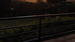 A sunset over a hilly landscape with a metal railing in the foreground. - Cabina Mandarina  (Provincia de Puntarenas)