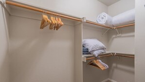 A walk-in closet with wooden hangers, shelves with folded clothes, and a neatly organized space. - Snug Home in Frisco/Little Elm (Little Elm)