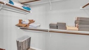 Un placard de rangement avec des étagères en bois, une boîte en carton et des couvertures pliées.