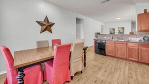 Une cuisine moderne avec des meubles en bois, un four encastré et un coin repas comprenant une table et des chaises en bois.