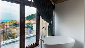 Un baño moderno con una bañera independiente, ventanas amplias y vistas a la ciudad.