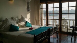 A bed with white linens and teal pillows, a teal throw blanket, and a wooden headboard. - Closenberg Hotel  (Galle)