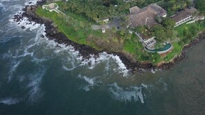 An aerial view of a coastal property with a swimming pool, a beach, and a rocky shoreline. - Closenberg Hotel  (Galle)