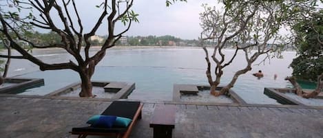 A serene outdoor area with a pool, lounge chairs, and a view of the water.
