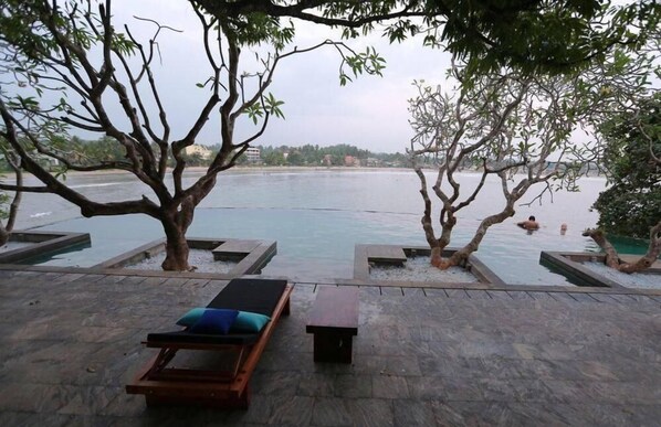 Un espacio exterior tranquilo con piscina, sillas de descanso y vistas al agua.