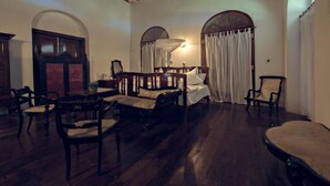 A room with a bed, wooden chairs, a table, and a mirror. - Closenberg Hotel  (Galle)