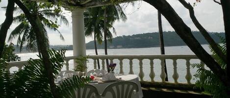 A table set outdoors with a view of a body of water and palm trees.