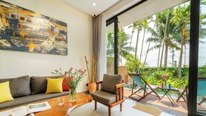 A modern living room with a sofa, armchair, and a dining table with a book and vases.