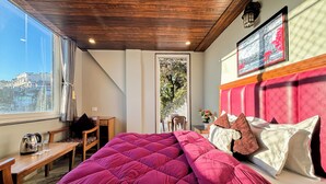 Een slaapkamer met een groot bed, houten meubels, uitzicht op de stad en een rode hoofdbord.