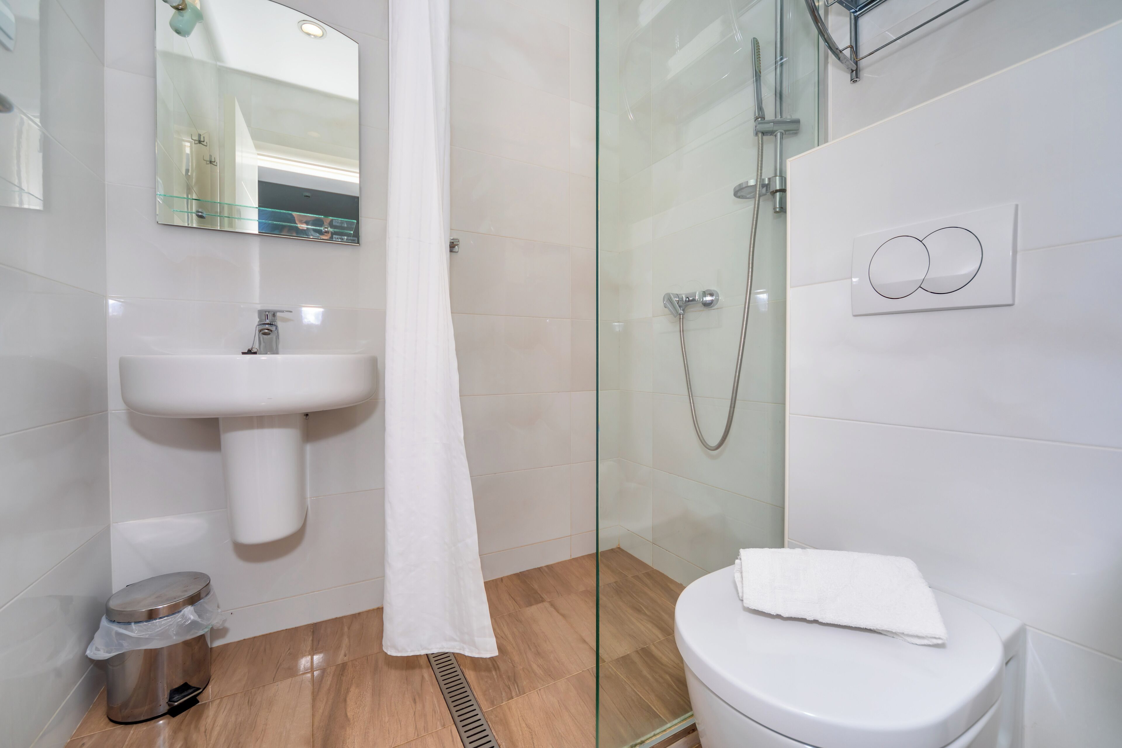 Un baño con cabina de ducha de vidrio, un lavamanos blanco y un inodoro.