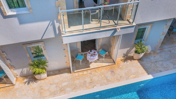 A two-story building with a balcony, a pool, and outdoor seating. - Apartments Fortunella (Petrovac)