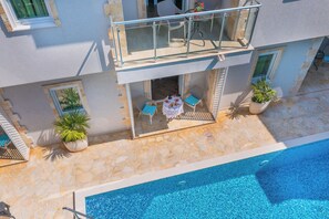 A two-story building with a balcony, a pool, and outdoor seating.