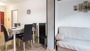 En matplats med ett bord för fyra personer, en soffa och en väggklocka.