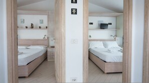 A mirrored view of a hotel room with two beds, a TV, and a shelf with decorative items. - Profumo di Mare in Olbia (Olbia)