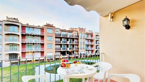 A balcony with a table set for two, overlooking a row of multi-story residential buildings.