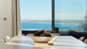Una mesa de comedor con un cuenco de piñas, vista al mar y un interior moderno.