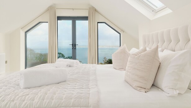 Un dormitorio con una cama grande, un tragaluz y vista al mar.