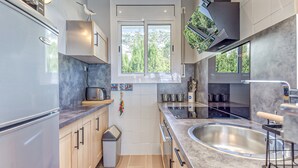 Une cuisine moderne dotée d’une grande fenêtre, d’appareils électroménagers en acier inoxydable et offrant une vue sur les environs.