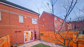 A brick house with a small backyard, a wooden fence, and a tree. - Beautiful Luxurious Home by LFC Stadium (Liverpool)