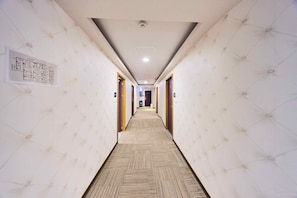 A hotel hallway with patterned walls, a carpeted floor, and doors on both sides. - Travel Time Hotel (Taipei)