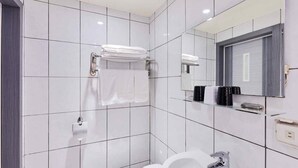 Um banheiro moderno com azulejos brancos, vaso sanitário, pia, espelho e porta-toalhas.