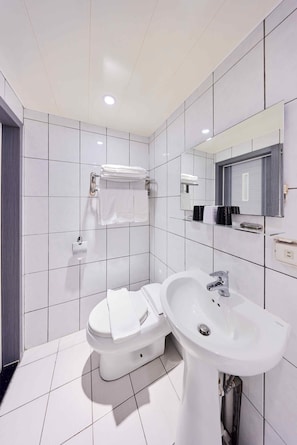 A modern bathroom with white tiles, a toilet, a sink, a mirror, and a towel rack. - Travel Time Hotel (Taipei)