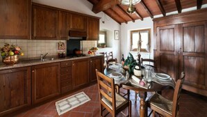 Une cuisine avec des meubles de rangement en bois, un pare-feu en carrelage, une table à manger pour quatre personnes et un luminaire suspendu.