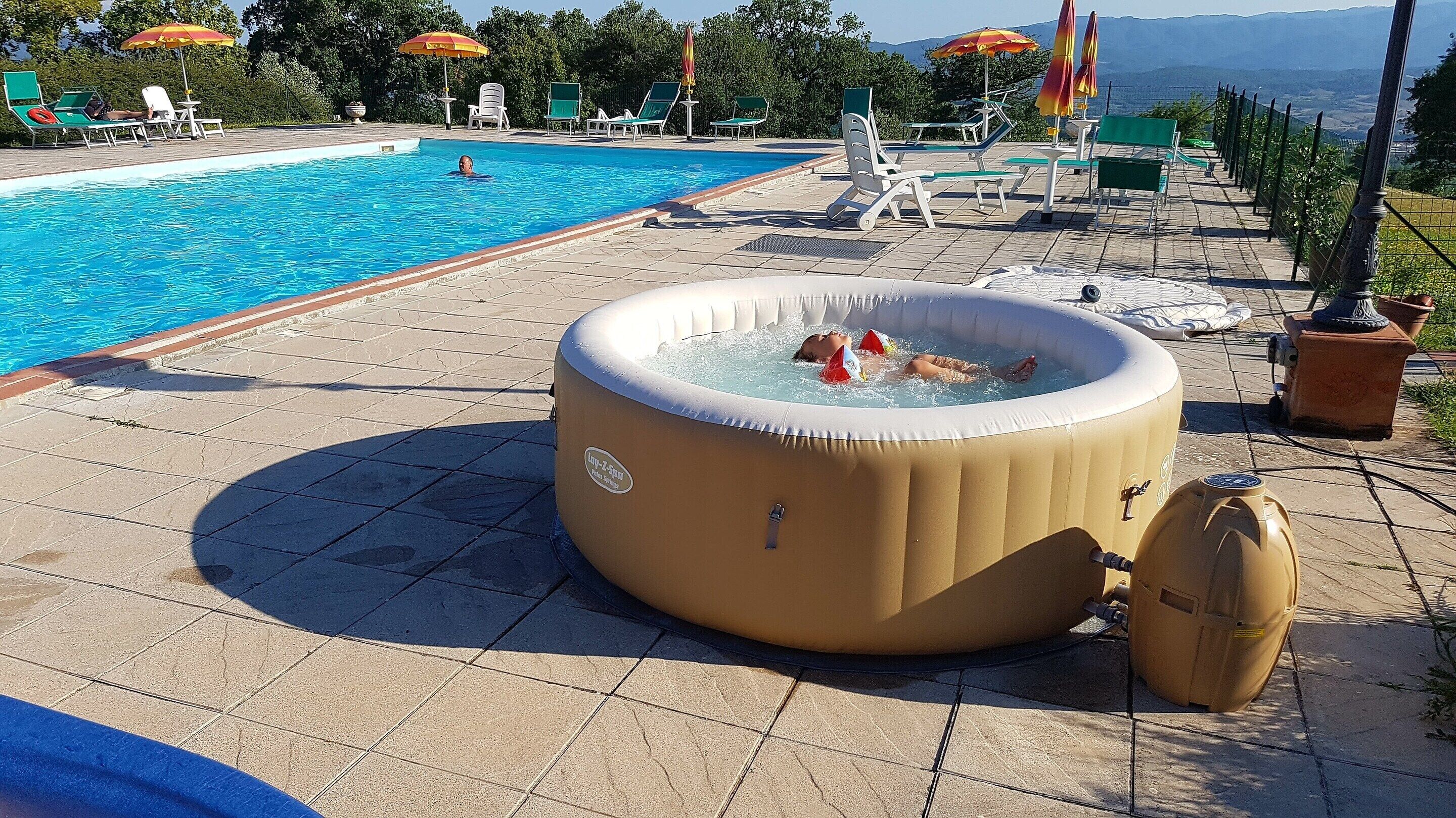 A swimming pool with lounge chairs and a hot tub.