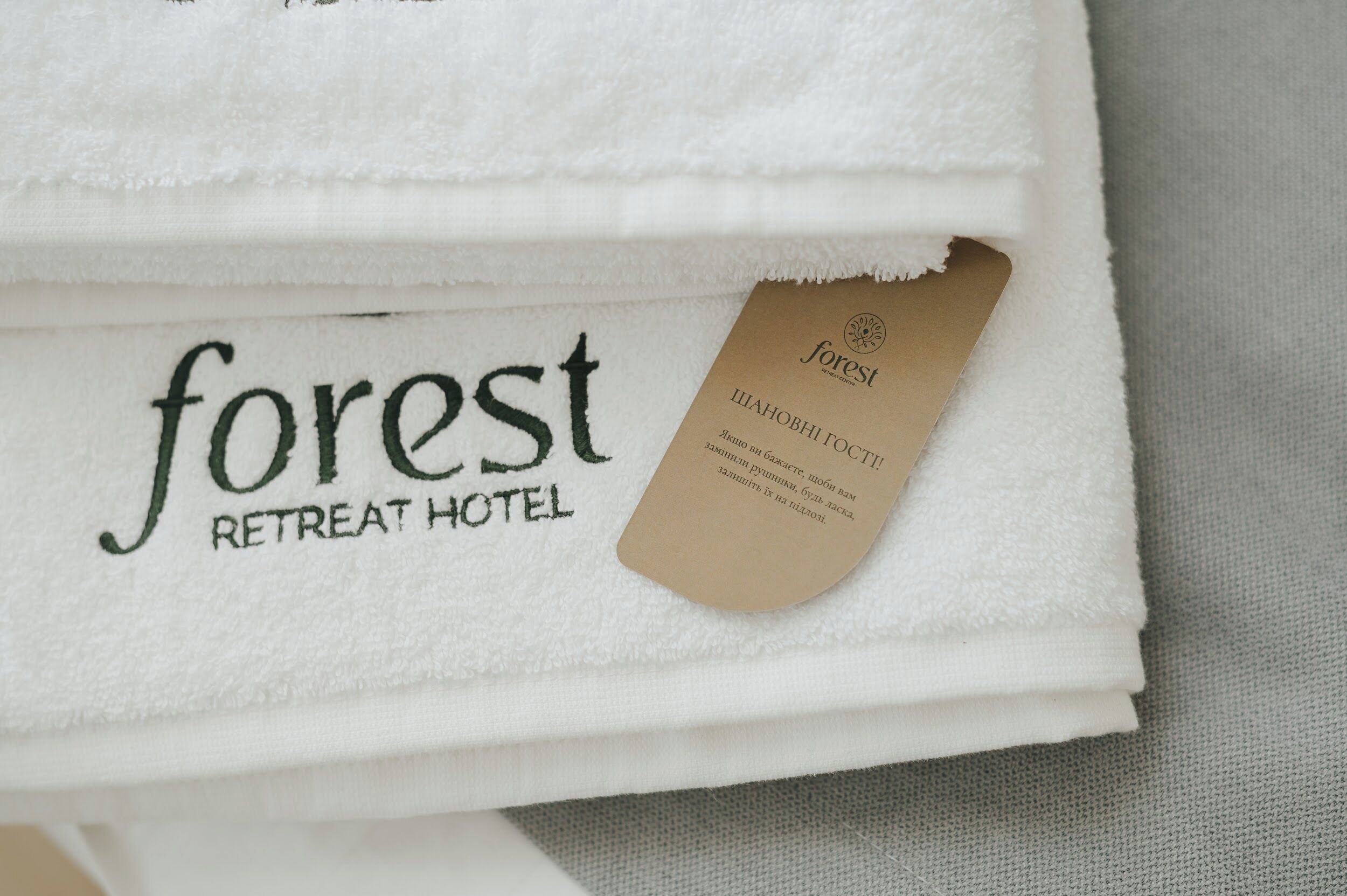 Een gevouwen witte handdoek met de tekst “forest RETREAT HOTEL” en een bijbehorend label met dezelfde naam.