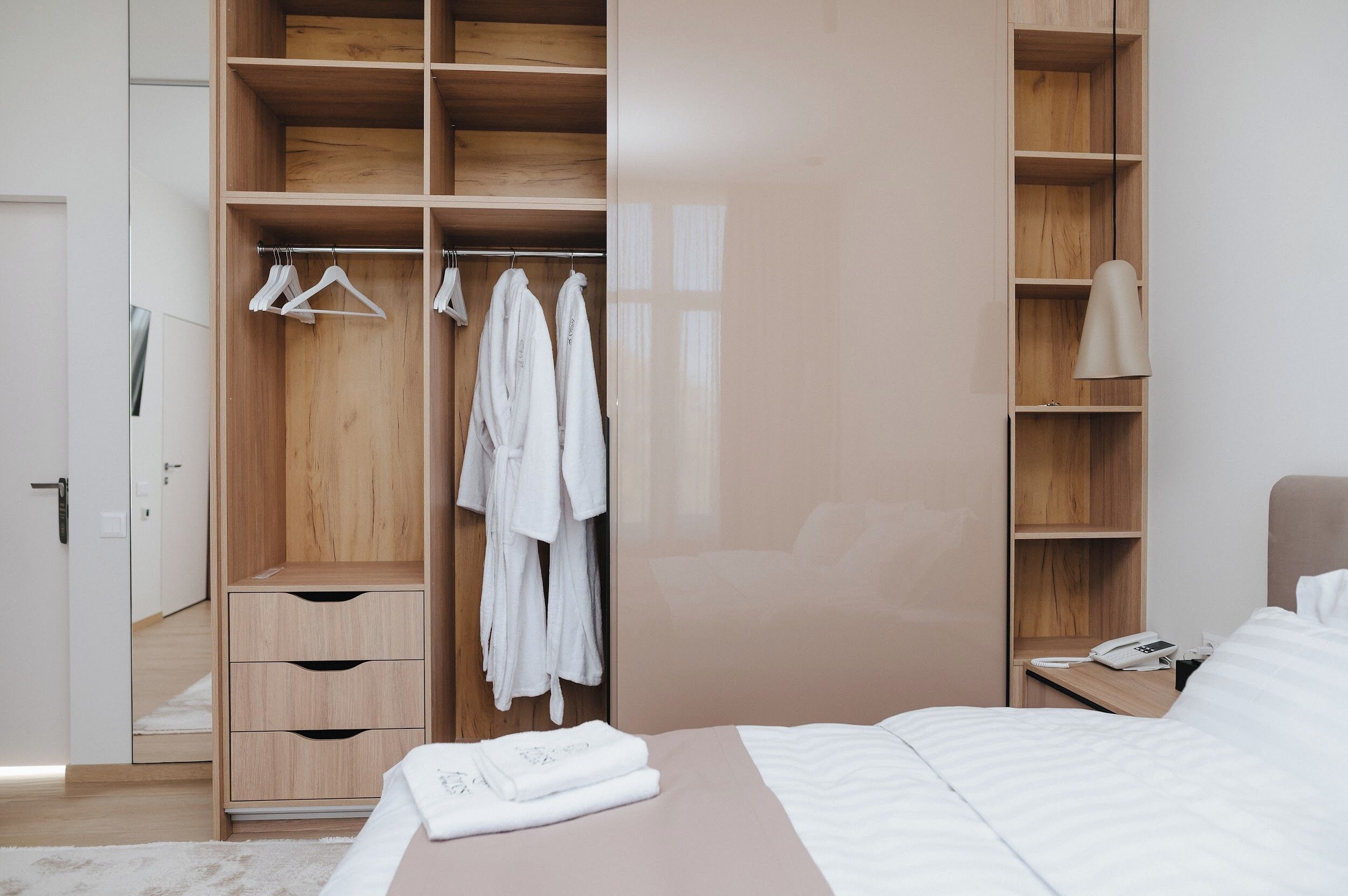 A bedroom with a bed, a wooden wardrobe, and a bedside table with a lamp.