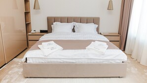 A neatly made bed with white linens and towels, a wooden nightstand with a phone, and a beige headboard. - Forest Retreat Center (Kyiv)