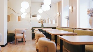 A modern restaurant interior with round tables, cushioned seating, and pendant lighting. - Forest Retreat Center (Kyiv)