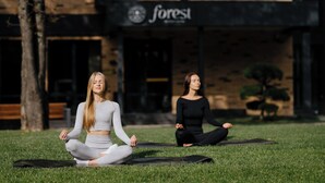 Two people meditating on a grassy area in front of a building with a 'forest' sign. - Forest Retreat Center (Kyiv)
