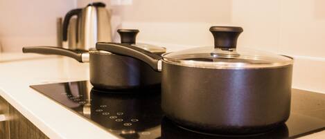 Una cocina con tope de inducción negro, una olla y un hervidor.